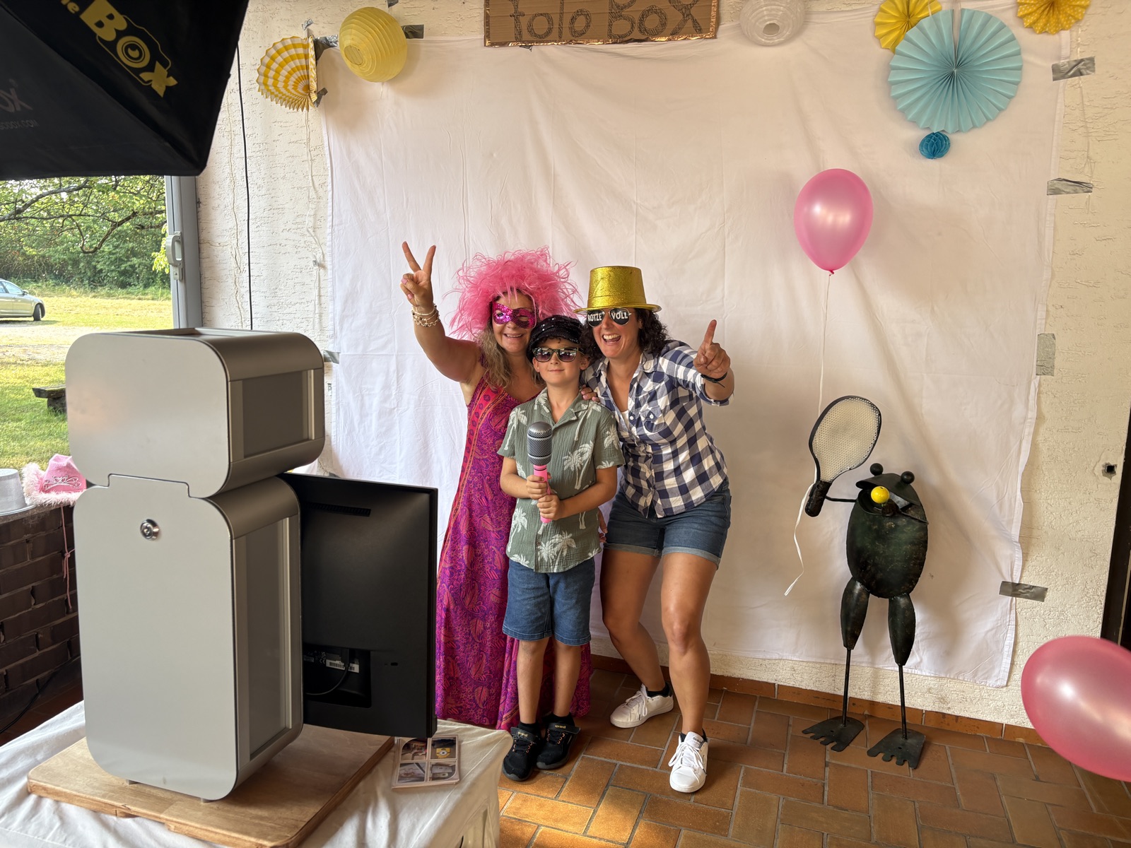Drei Gäste mit Perücke, Goldhut und Sonnenbrille posieren vor der Fotobox